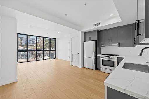 A modern kitchen with wooden floors and white appliances.