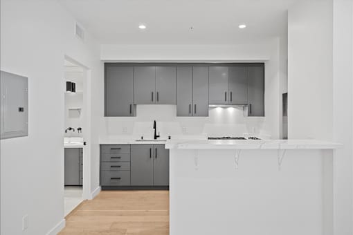 A modern kitchen with a white countertop and grey cabinets.