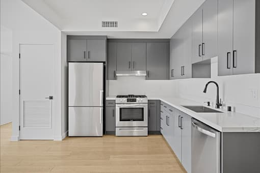 A modern kitchen with stainless steel appliances and wooden floors.
