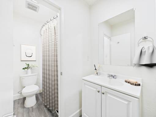 A white bathroom with a toilet, sink, and shower.