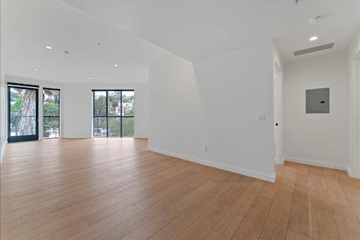 A large empty room with wooden floors and white walls.