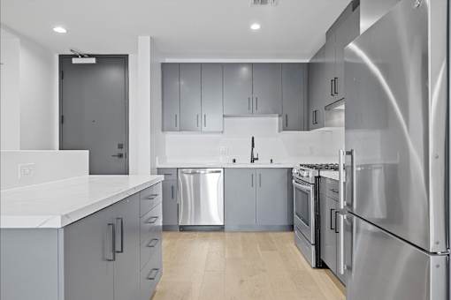 A modern kitchen with stainless steel appliances and wooden floors.