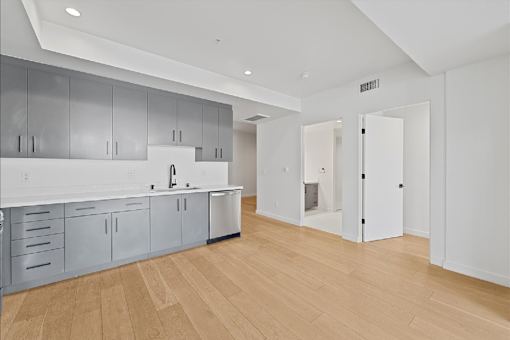 A kitchen with white cabinets and a wooden floor.