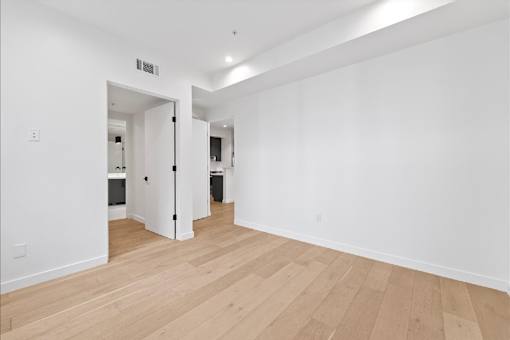 A room with a white wall and wooden flooring.
