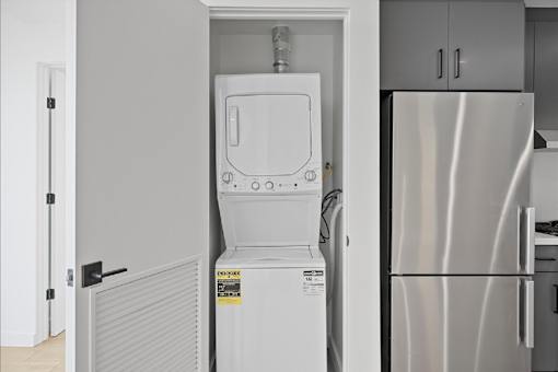 A white dishwasher is in a kitchen next to a refrigerator.