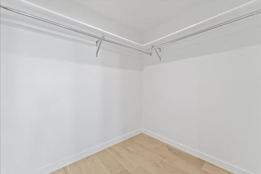 A white wall with a wooden floor and a white ceiling with a metal rod.