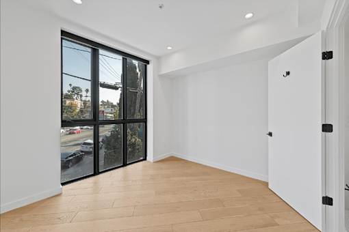 A room with a sliding glass door and wooden flooring.