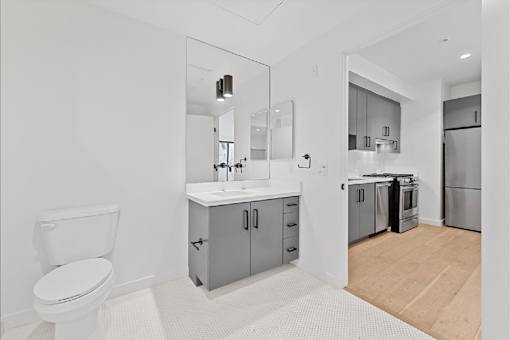A white toilet is in a bathroom with a sink and mirror.