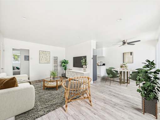 A living room with a white couch, a wooden chair, and a television.