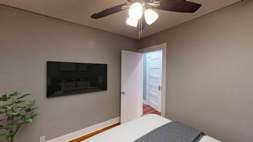 A room with a ceiling fan and a door leading to another room.