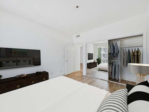 A bedroom with a large bed and a wardrobe with clothes hanging.