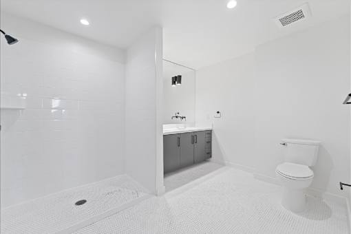 A white bathroom with a toilet, sink, and shower.