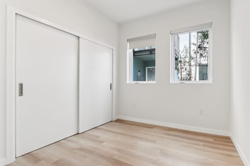 A room with a white door, a mirror, and a window.