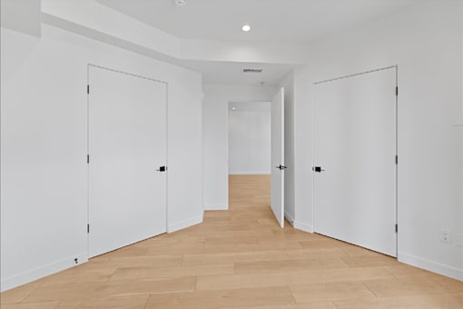 A long hallway with white doors and wooden floors.