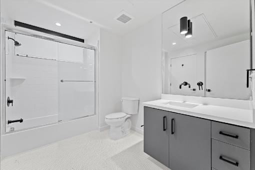 A white bathroom with a toilet, sink, and shower.