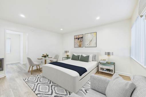 A bedroom with a large bed, a chair, a table, and a couch.