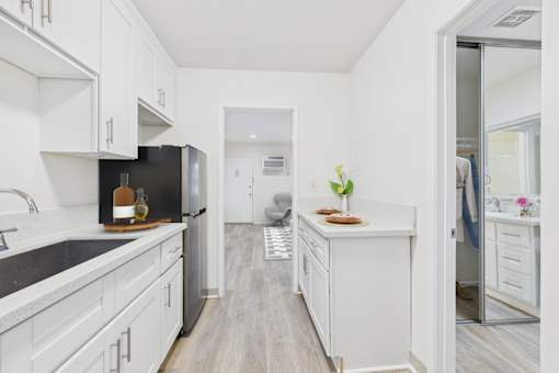 A kitchen with white cabinets and a black fridge.
