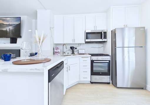 A kitchen with white cabinets and appliances.