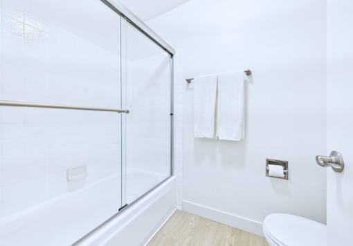A white bathroom with a towel hanging on the wall.