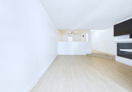 A long, empty room with wooden floors and white walls.