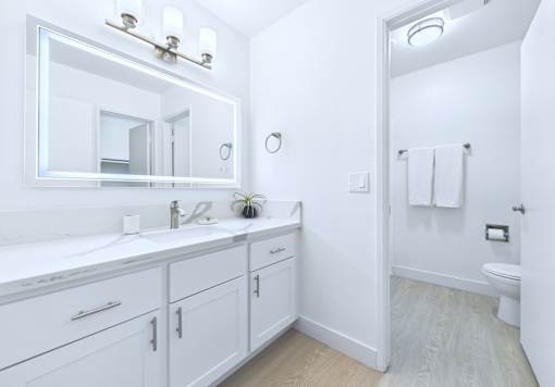 A white bathroom with a large mirror and a white sink.