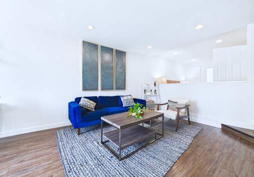 A blue couch sits in a living room with a glass coffee table in front of it.