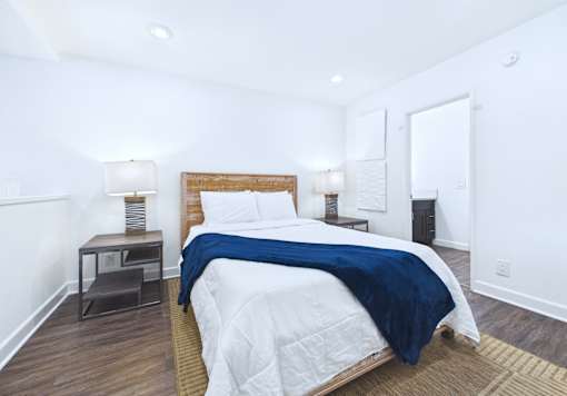 A bedroom with a bed, nightstand, and lamp.