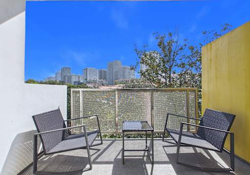 A patio with a table and chairs overlooking a city skyline.