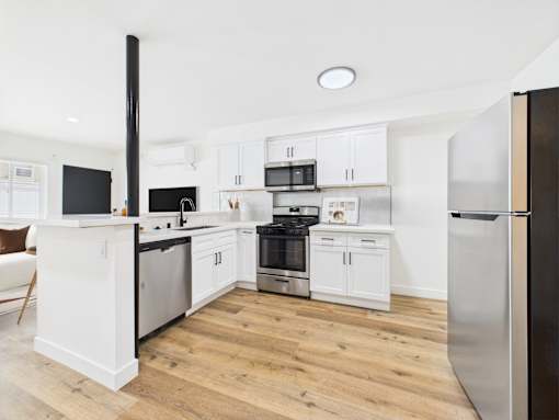 A modern kitchen with white cabinets and stainless steel appliances.