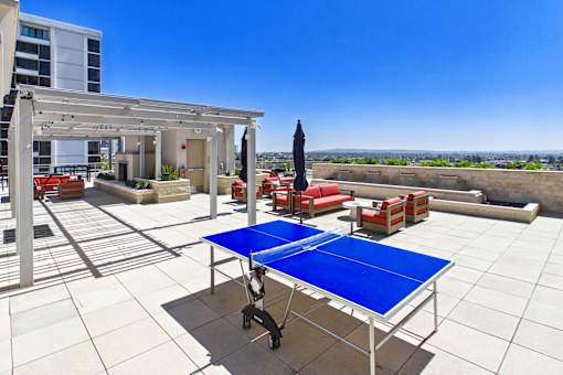 A blue table is in the middle of a white tiled patio.
