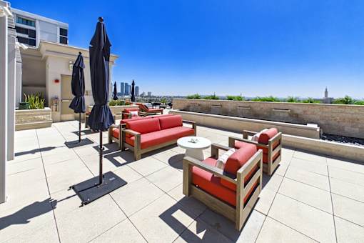 A patio with red couches and black umbrellas overlooking a waterway.