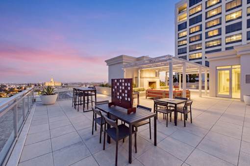 A patio with a table and chairs overlooking a cityscape at dusk.