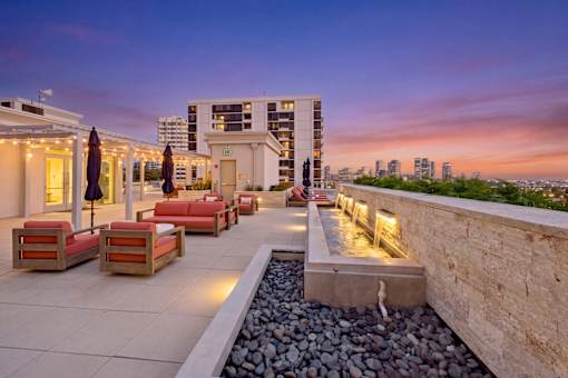 A rooftop patio with a water feature and seating area.