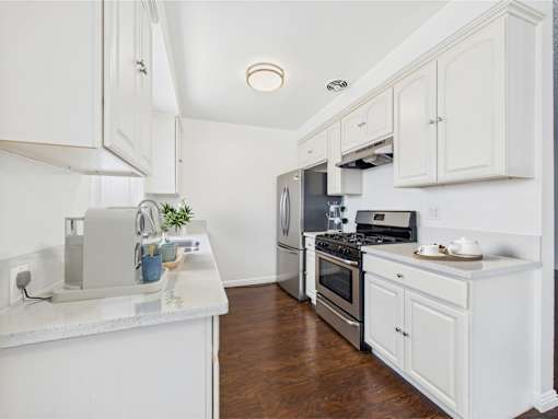 A kitchen with white cabinets and a marble countertop.