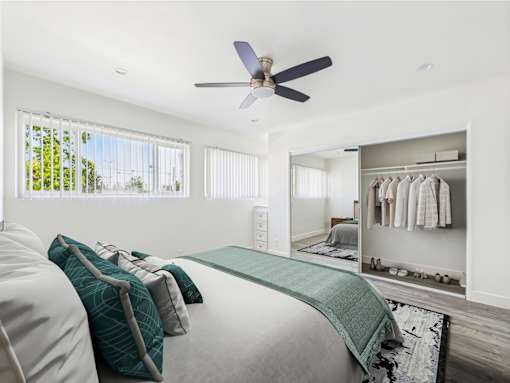 A bedroom with a bed, a ceiling fan, and a wardrobe.