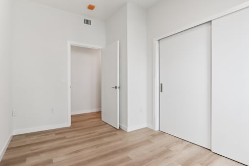 A room with white walls and wooden flooring with two doors.
