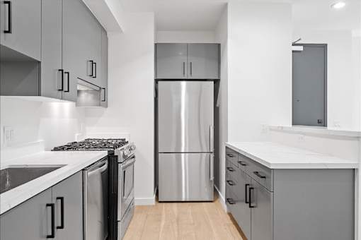 A modern kitchen with a stainless steel refrigerator and black and white cabinets.
