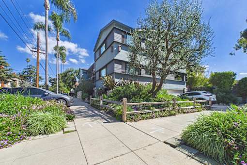 A modern two-story house with a grey exterior and a well-maintained garden in front.