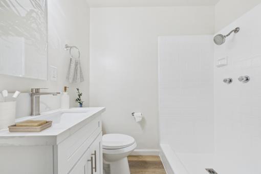 A white bathroom with a toilet, sink, and shower.