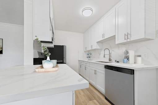 A kitchen with white cabinets and a marble countertop.