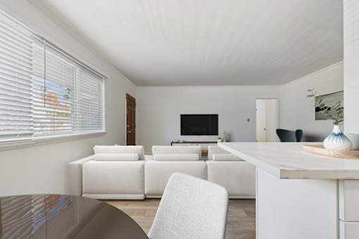 A white living room with a television and a white chair.