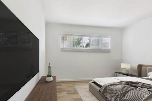 A bedroom with a large bed and a flat screen TV mounted on the wall.
