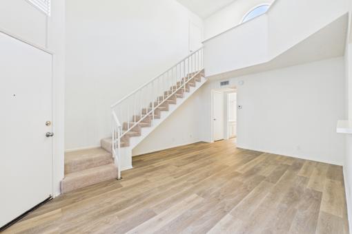 A white interior with a wooden staircase.
