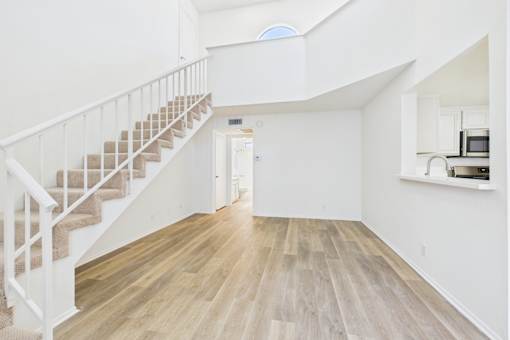A white interior with a staircase and a kitchen area.