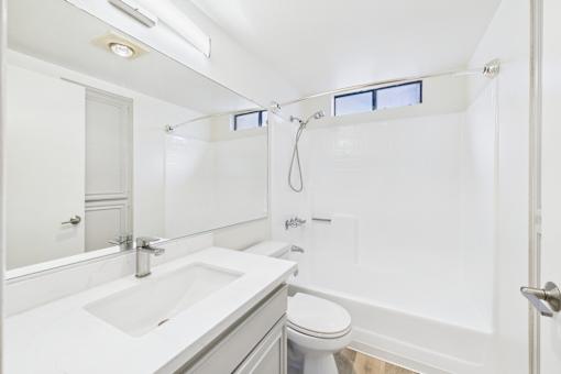 A white bathroom with a toilet, sink, and shower.
