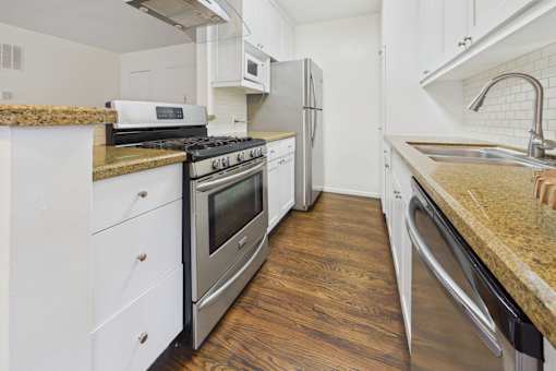A kitchen with white cabinets and a granite countertop.