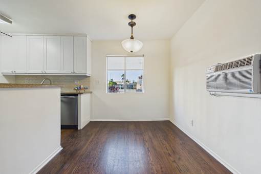 A kitchen with white cabinets and a wooden floor.