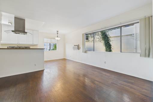 A spacious kitchen with wooden floors and white walls.