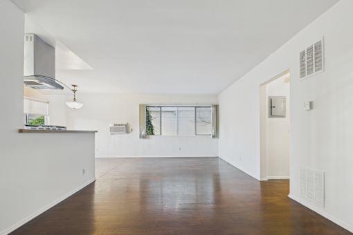 A spacious, empty room with wooden floors and white walls.