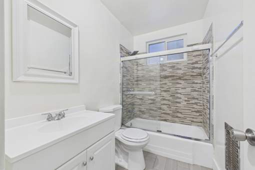 A white bathroom with a toilet, sink, and shower.